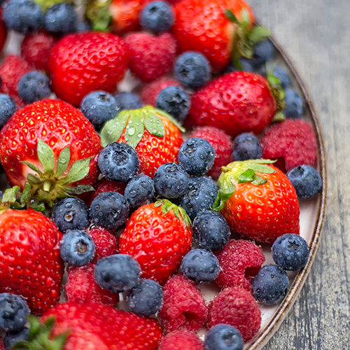 Fresh strawberries, blueberries, and raspberries on plate.