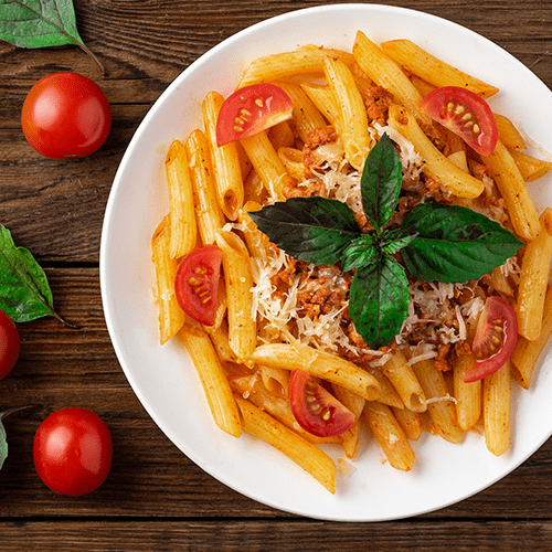 Penne pasta with tomato sauce and basil garnish.