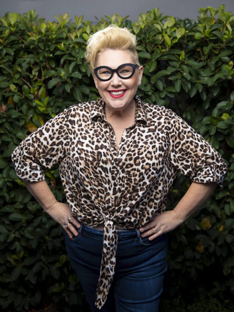 Woman in leopard print shirt smiling outdoors