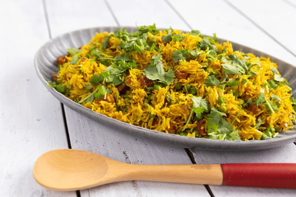 Spicy chorizo pilaf with peas, lemon and coriander leaves in a pan